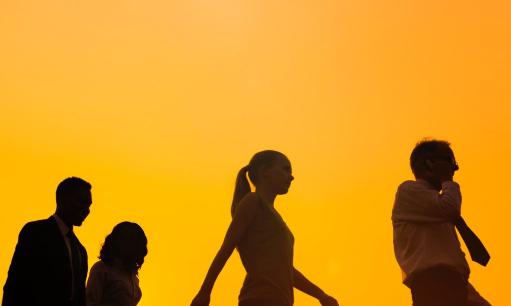 group walking in silhouette in orange background