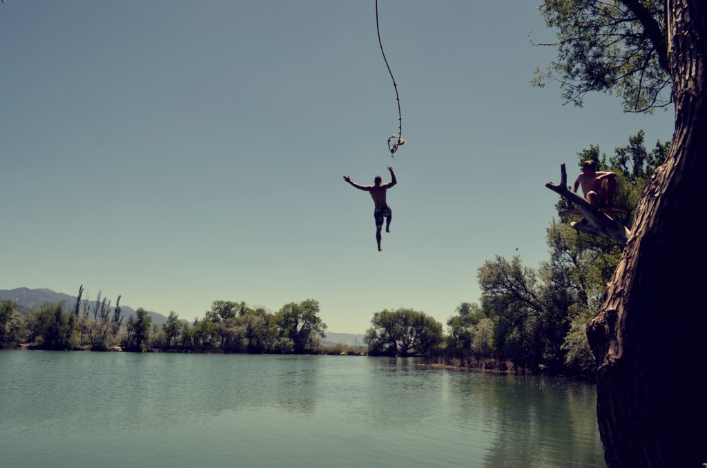 man about to fall into water from rope swing