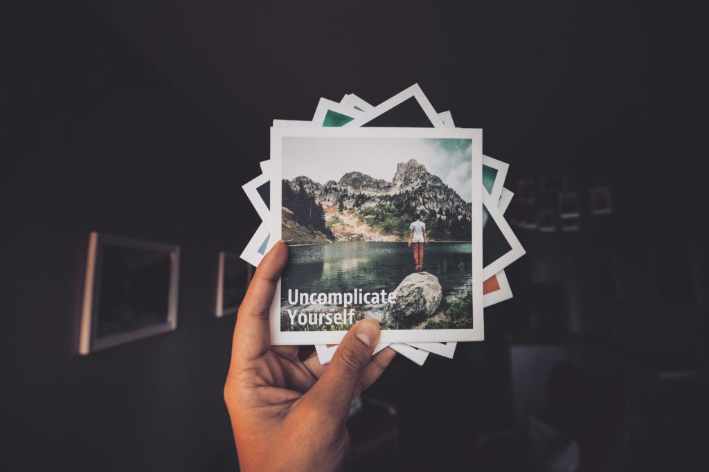 photos in hand with uncomplicate yourself written on top