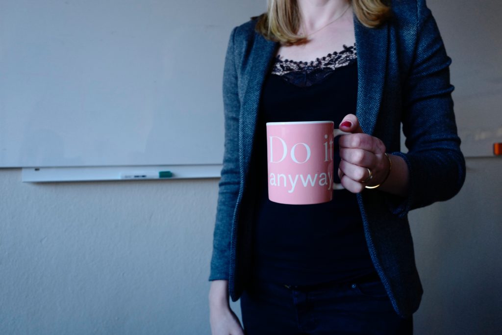 woman holding pink coffee mug that says do it anyway