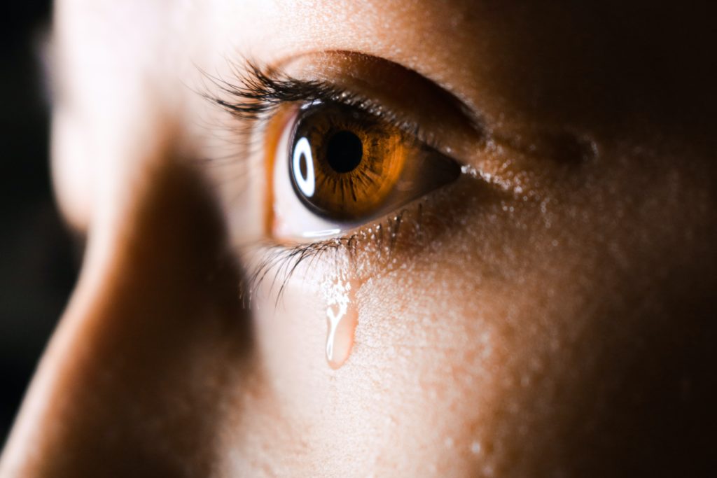 closeup of woman's eye with tear running down