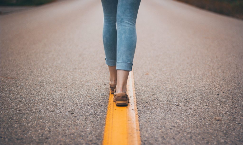 woman walking down center line of road